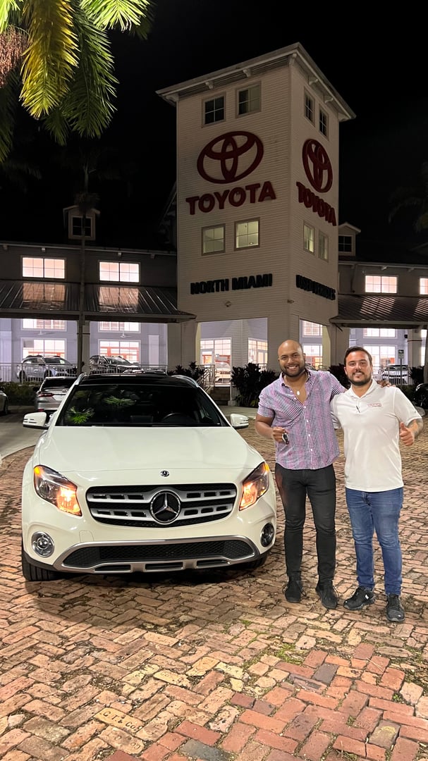 Cliente feliz posando con su nueva adquisición automotriz