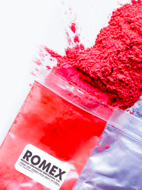 Red powder partially filling a transparent bag with a ROMEX label, some powder sprinkled outside the bag.