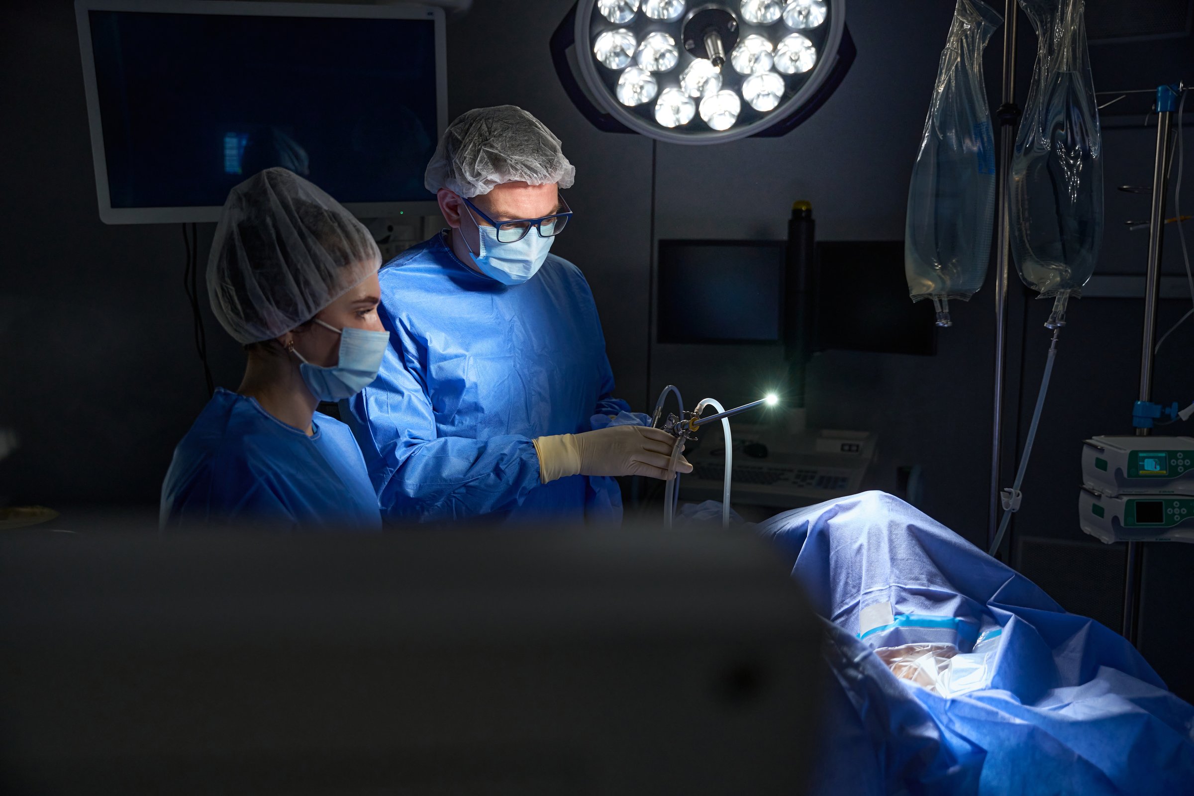 Male gynecologist working with his female assistant in the operating theatre. Gynecology