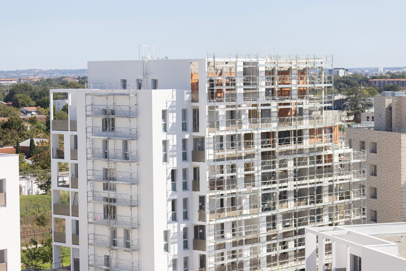 A contemporary residential building prominently displaying scaffolding as it progresses through its construction phase