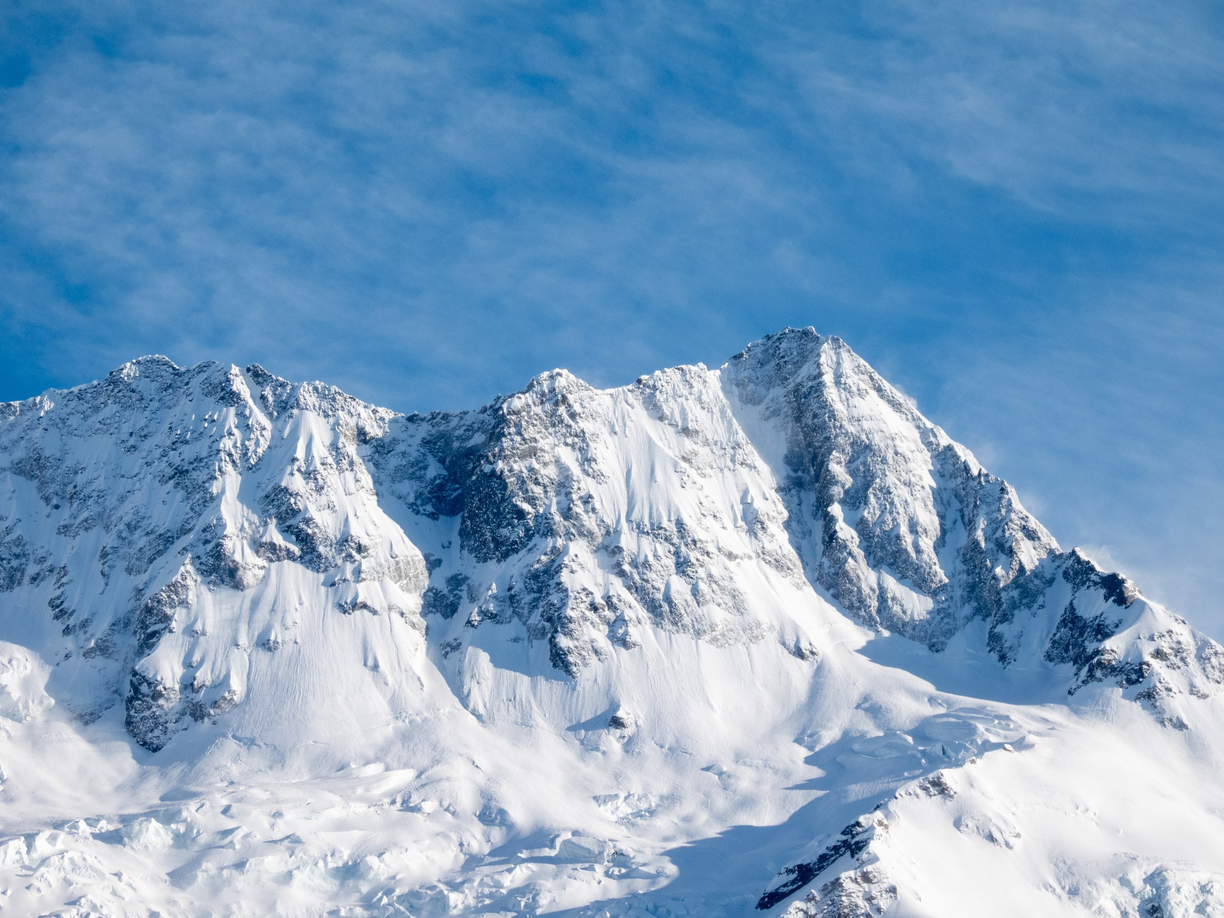 The sun rising in the east, but not yet appearing over the horizon of mountains, casts light over the Mt Cook Range in the southern alps of the South Island. This image was taken from Mt Cook Village on a cold and sunny morning on 12 November 2025.