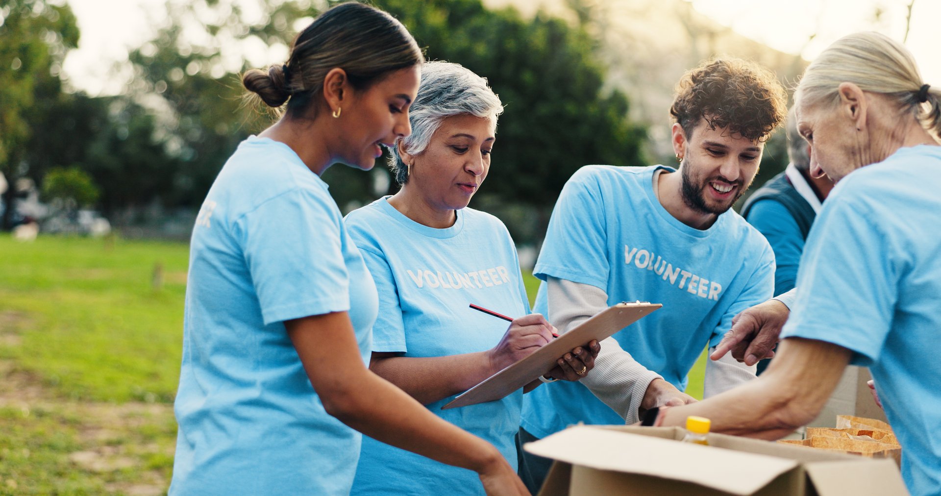 Woman, volunteer and writing with clipboard at park for donation, talk and notes for social responsibility. People, team and help with checklist, review or planning with sign up at charity event