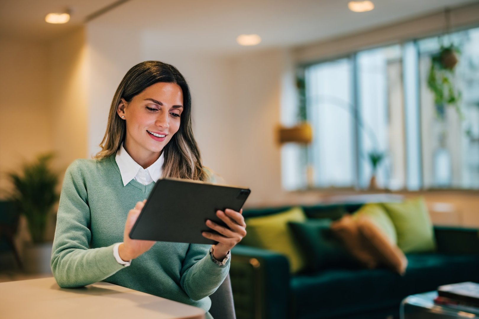 Businesswoman using a tablet, sitting in the living room.