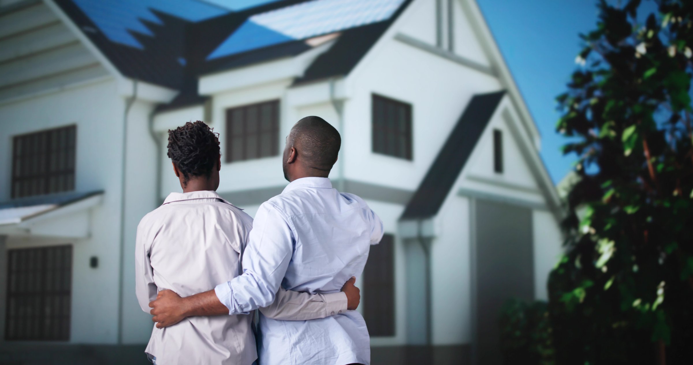 Couple In Front Of New House With Solar Panel Roof
