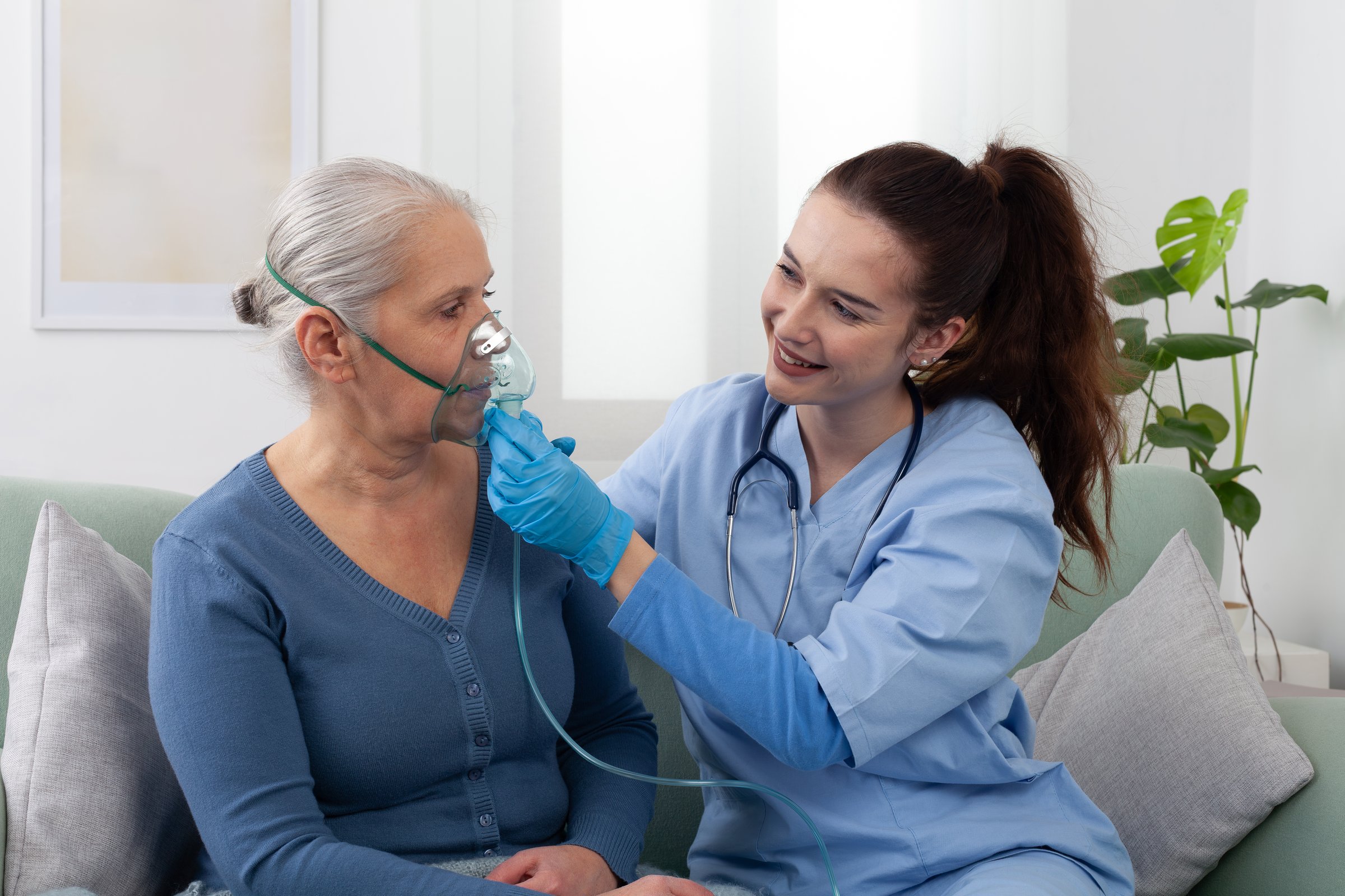 Nurse or doctor assists elderly woman using a respirator oxygen during home or clinic treatment. Respiratory care, medical support, and senior health care assistance