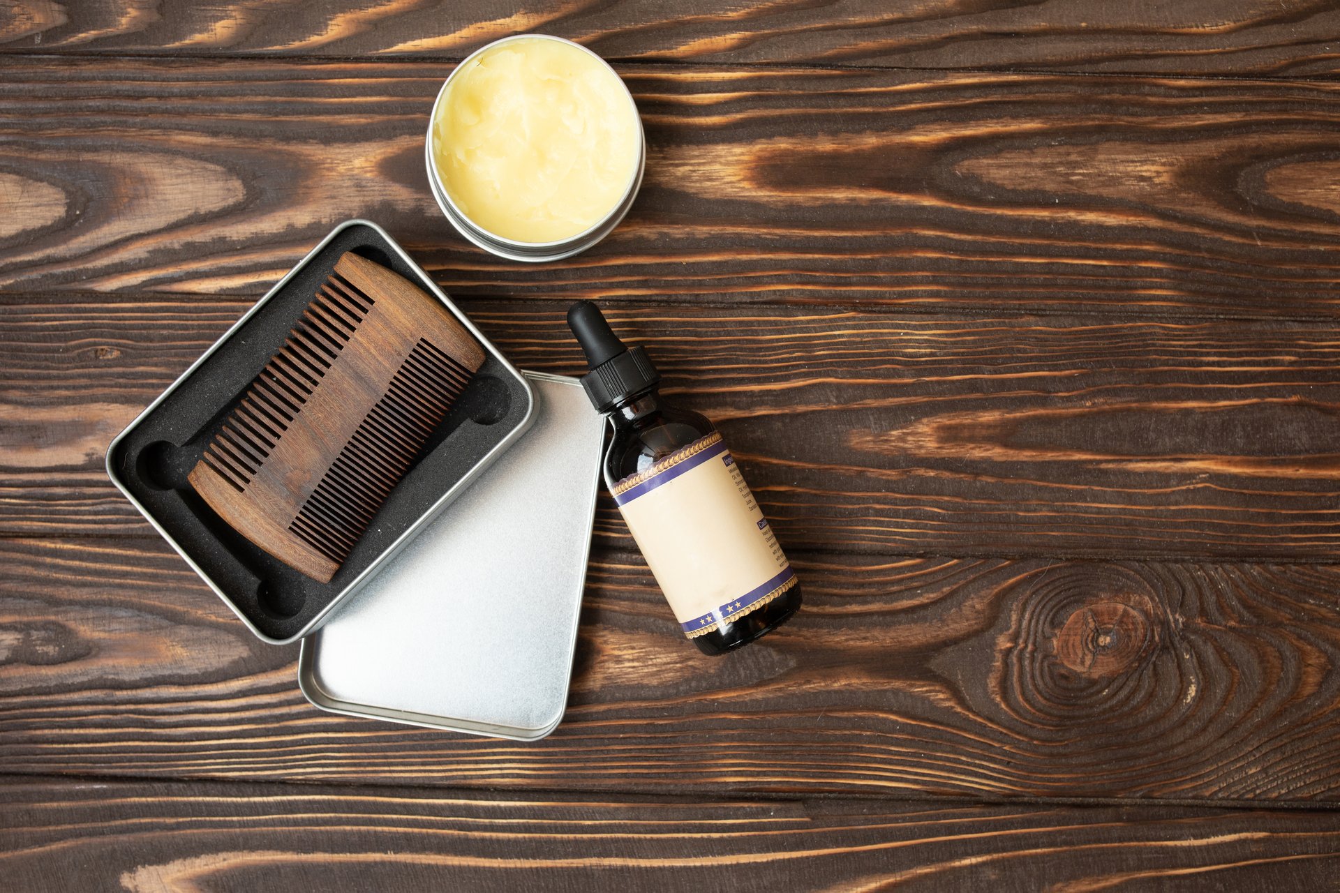 Old vintage barber shop tool on an old wooden background. Vintage wooden beard comb and beard oils.