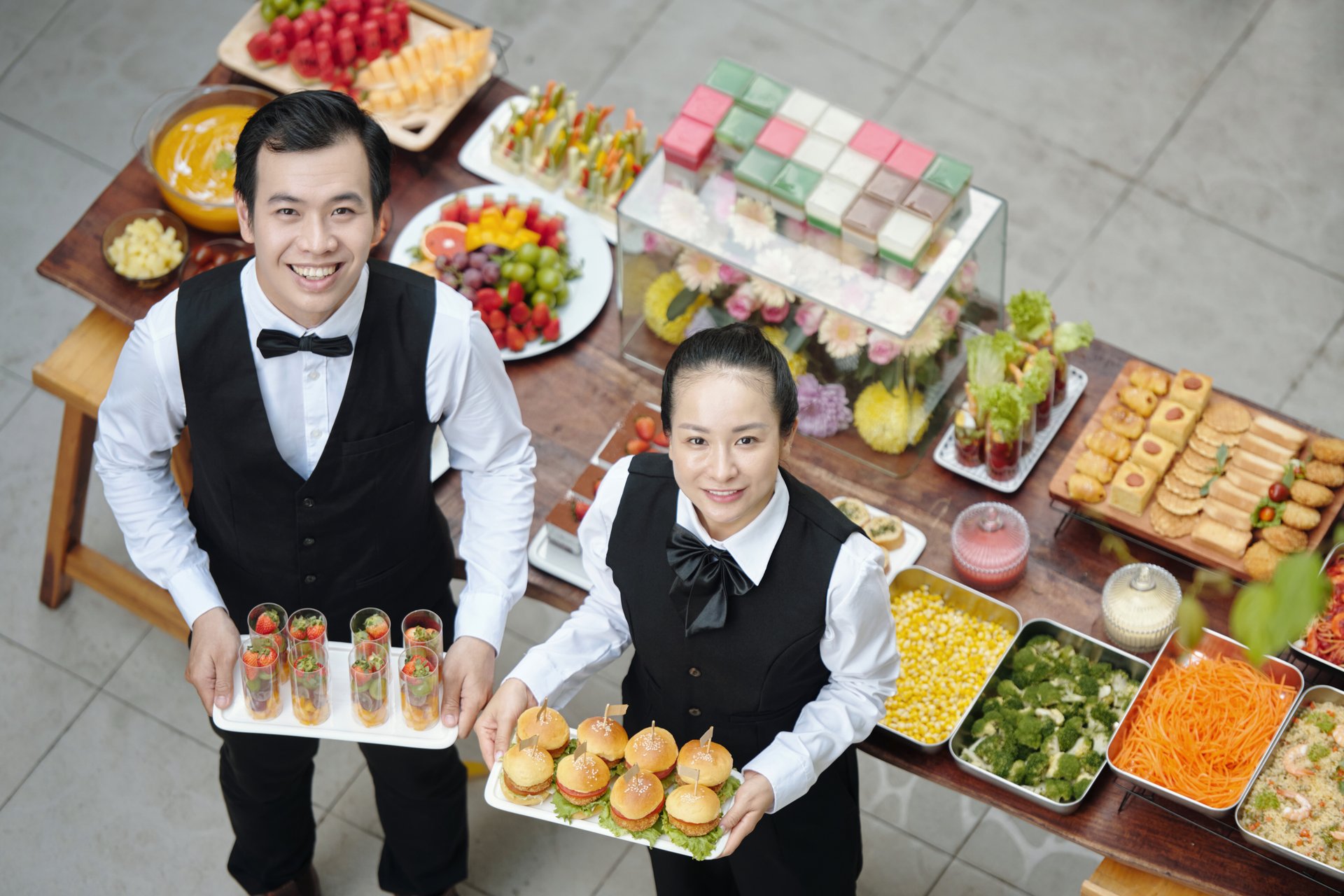 Two chefs presenting a variety of carefully prepared appetizers, buffet-style presentation in an elegant and sophisticated setting. Both chefs look excited and proud