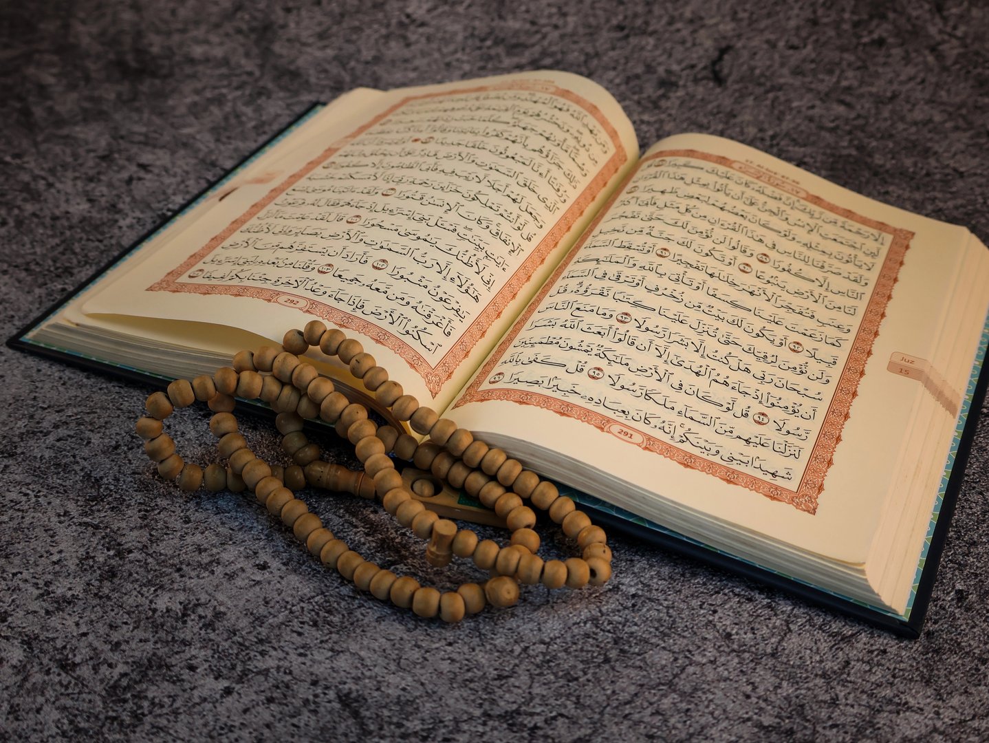 Opened page Holy Quran tasbih or rosary beads on top. Isolated background.