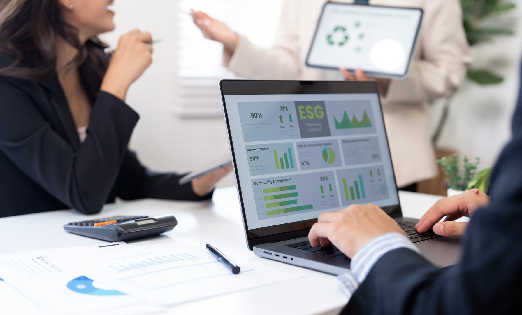 business professionals discussing ESG (Environmental, Social, and Governance) performance data displayed on a laptop screen during a corporate meeting