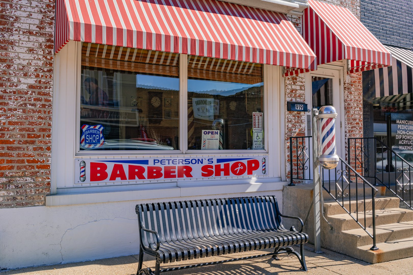 Princeton, IL, US-February 28, 2024: front entrance to old-fashioned, small town barbershop with bright red striped awning and classic barber pole.