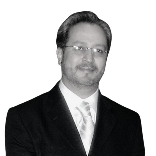 A man in a suit and tie, wearing glasses, with a neutral expression, on a plain white background.