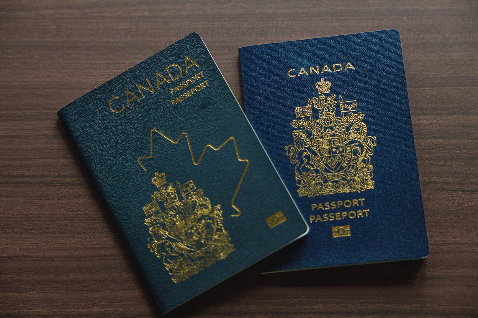 Vancouver, Canada - March 18,2025: Two Canadian passports placed on a wooden surface, showcasing the evolution of design