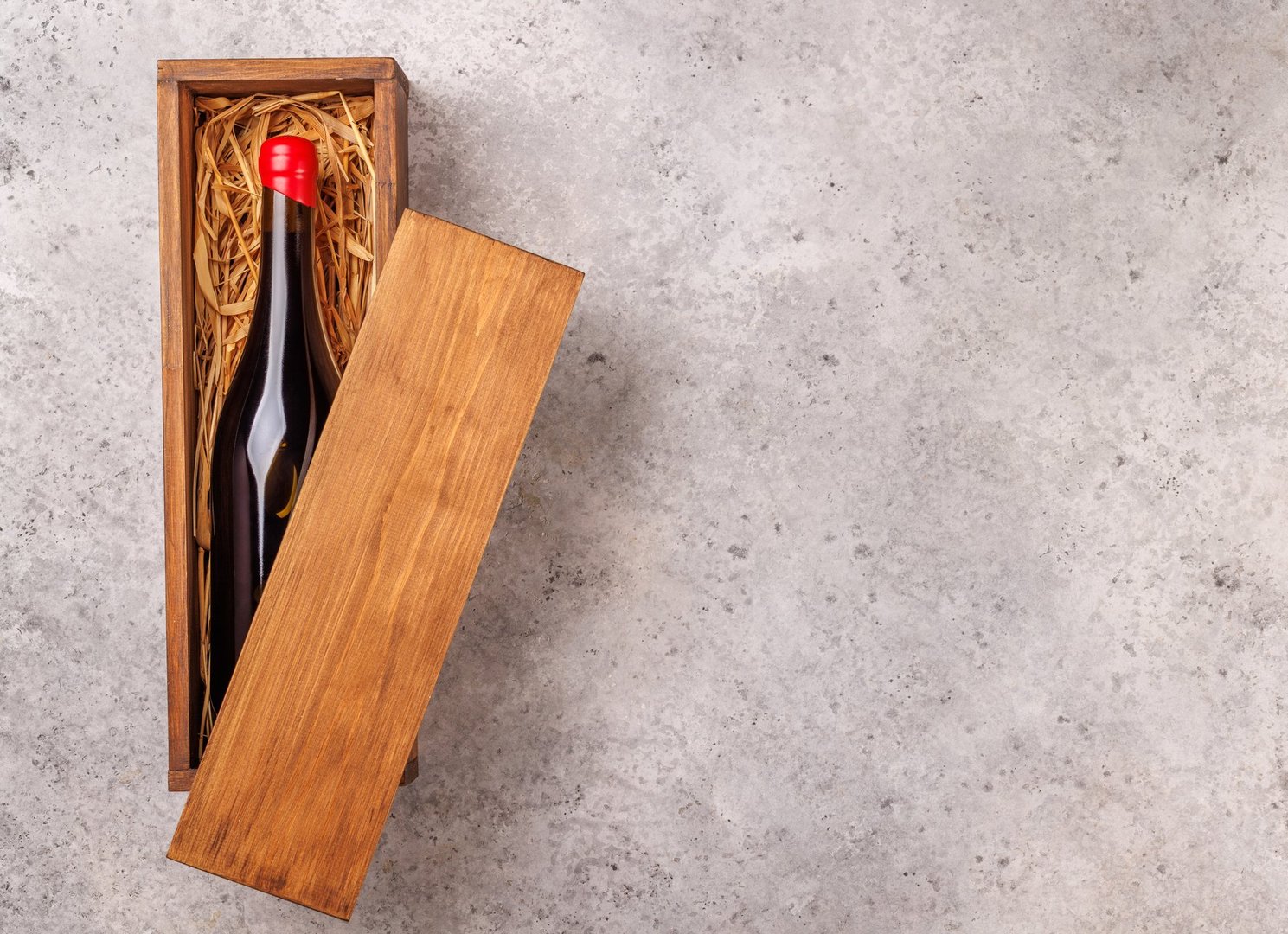 A red wine bottle elegantly placed inside a rustic wooden box, creating a classic and sophisticated presentation. Perfect for wine lovers, gift packaging, or cellar storage