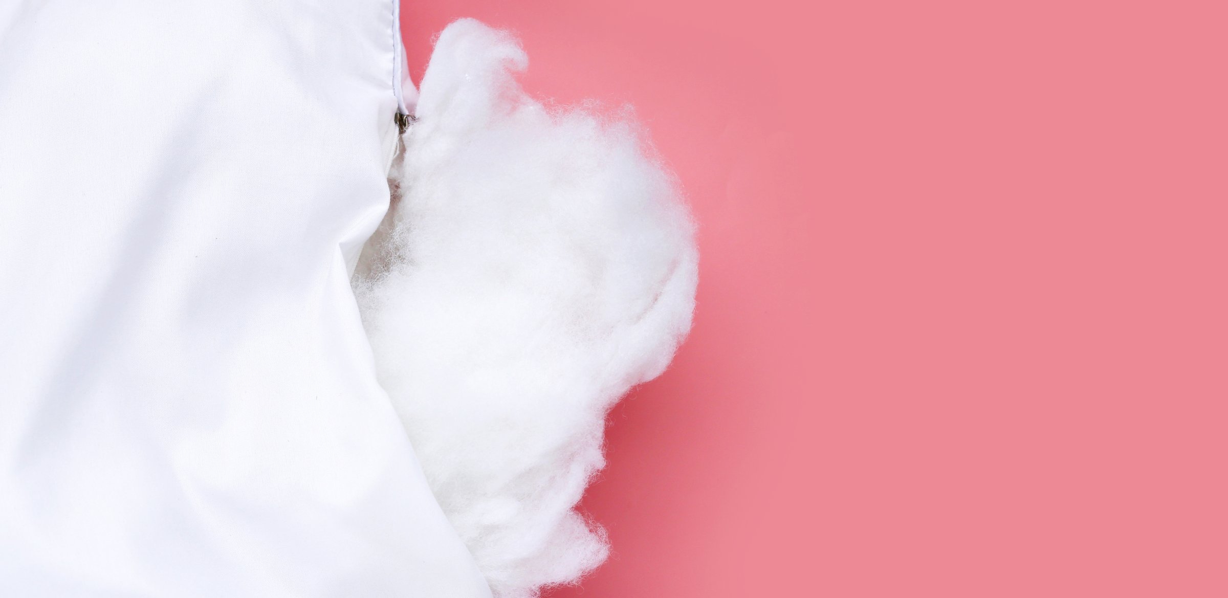 White pillow with polyester stable fiber on pink background.
