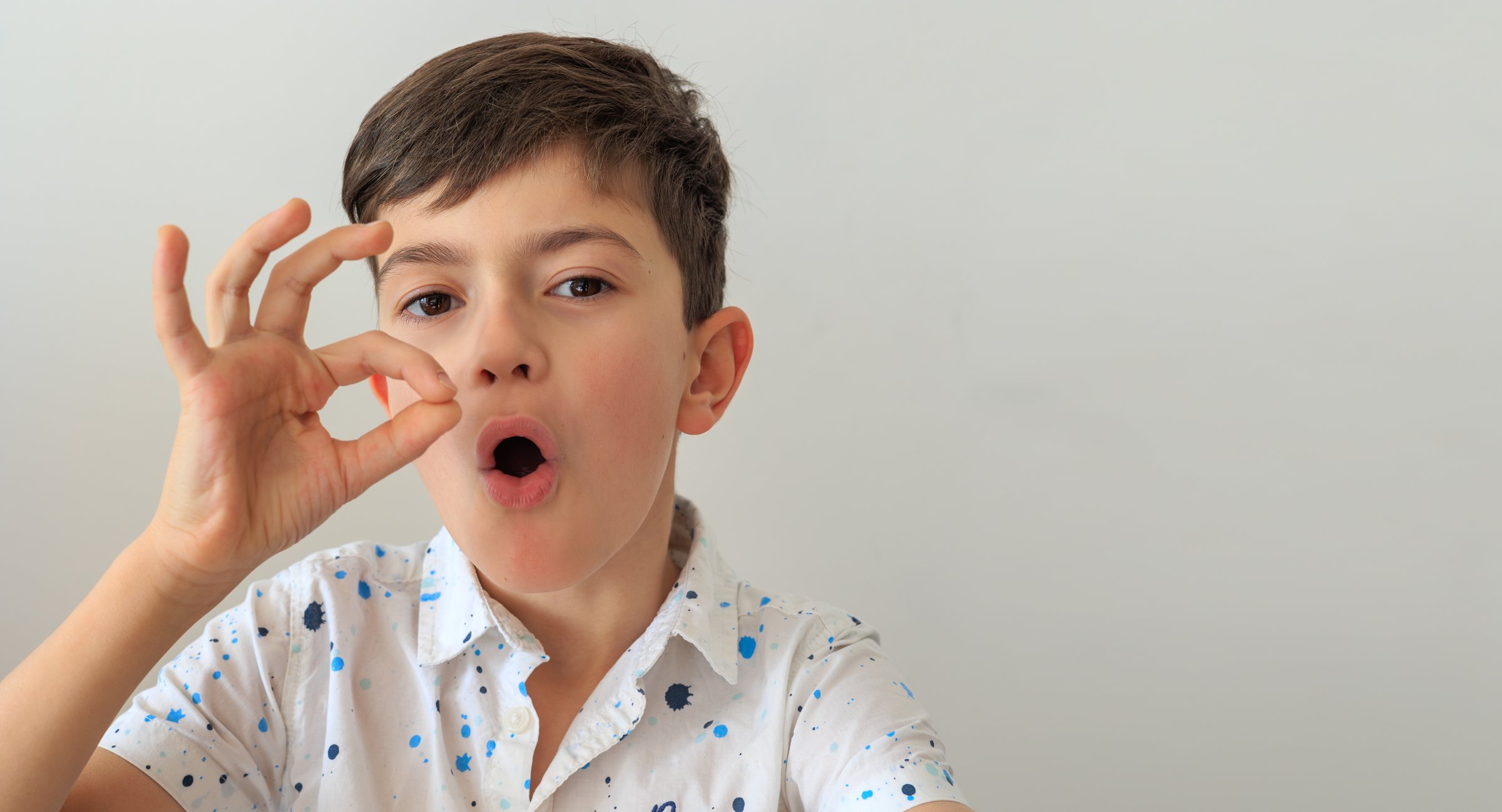A young boy, aged 6-8, practicing speech therapy exercises. The photo highlights themes of speech correction, developmental support, and language learning. Copy space
