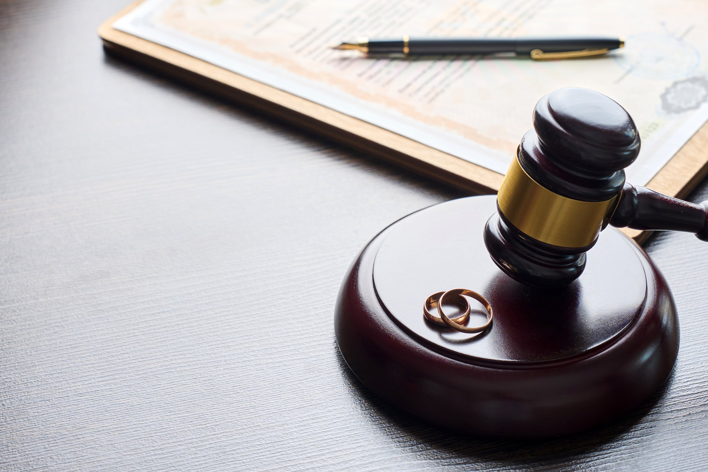 Divorce decree or marriage contract. Judge gavel with wedding rings and divorce decree. Marital agreement, legalities of divorce documents