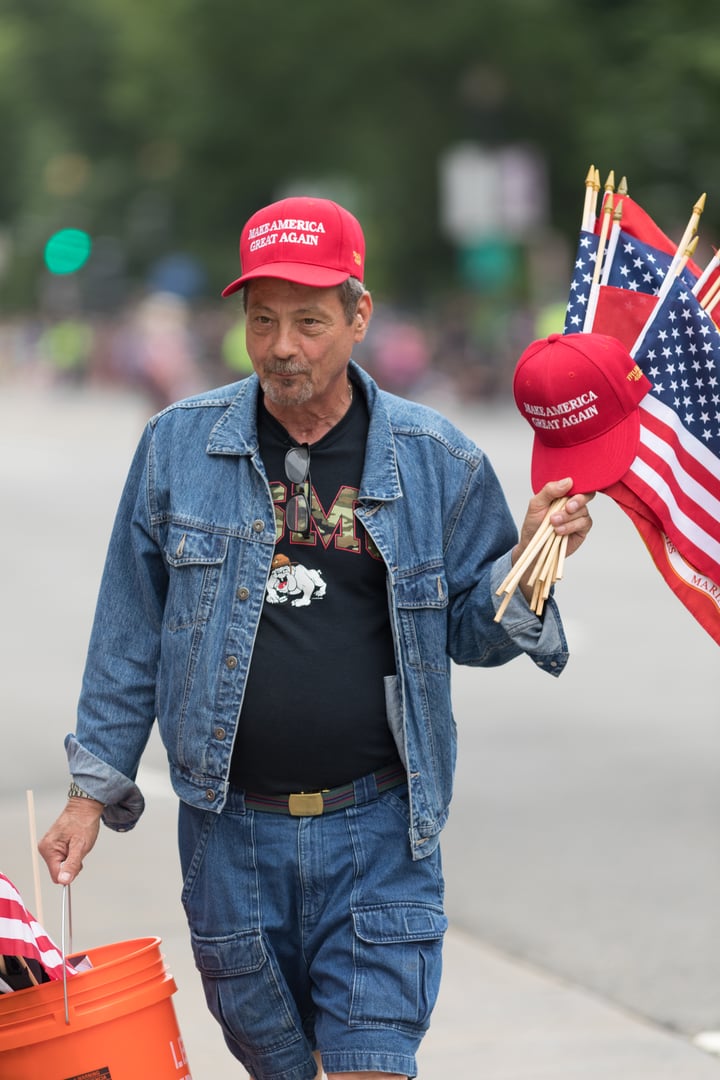 Man on the streets of washington DC, selling flags and hats with the words, Make America Great Again