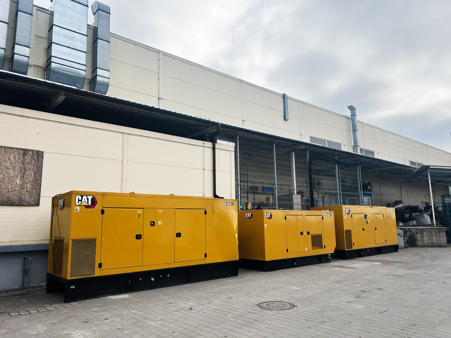 Lviv, Ukraine - February 12, 2025: Multiple industrial CAT generators aligned outside a commercial building for energy backup