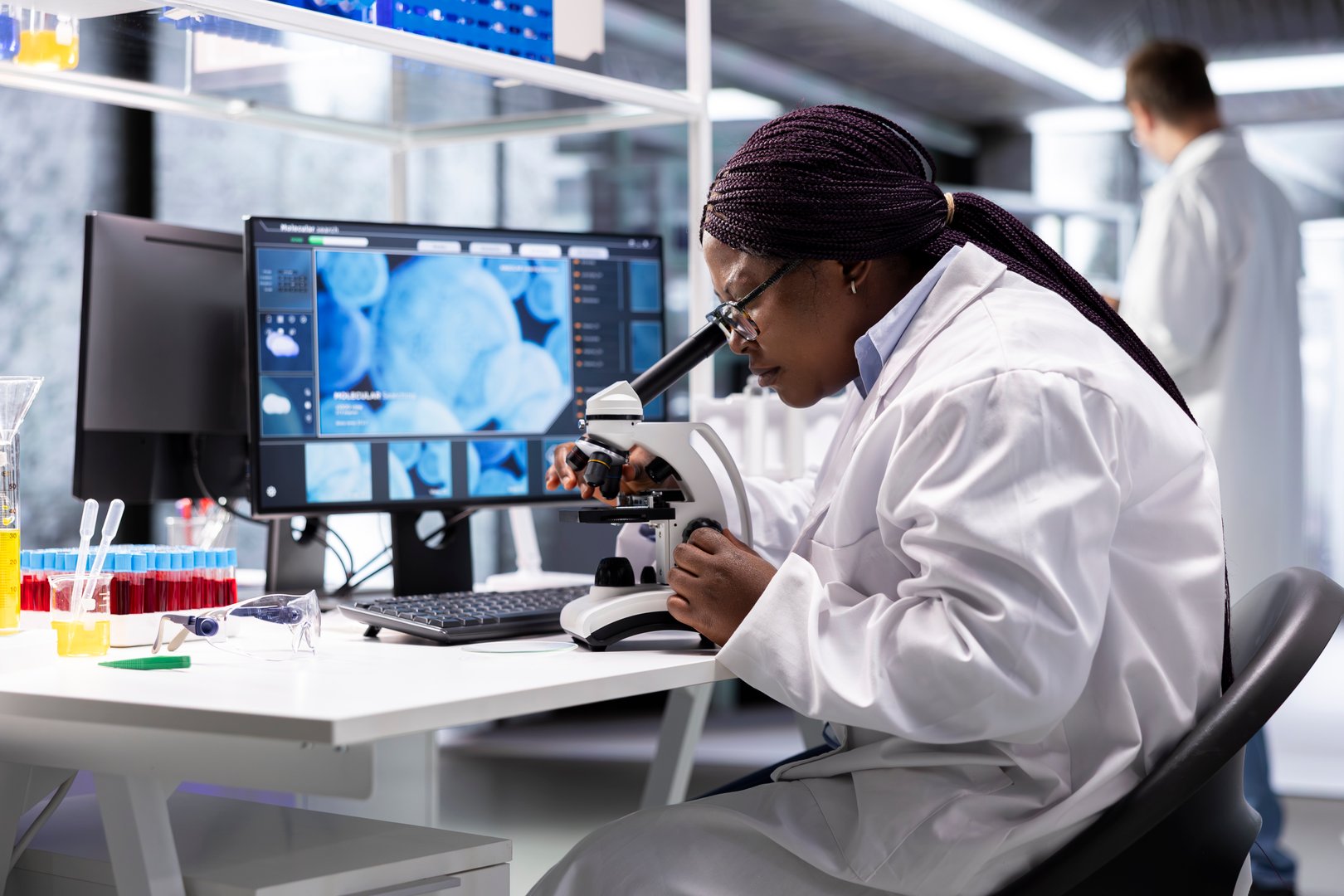Black scientist examining samples under microscope in a modern laboratory. Research work integrates biotechnology, molecular science and advanced diagnostics to shape medical discovery.