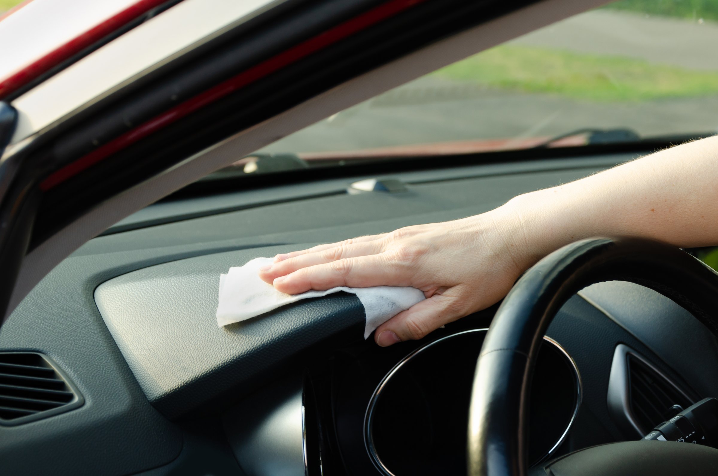 Close-up of a woman's hand wiping a car interior panel with a wipe. Disinfection of the car interior.