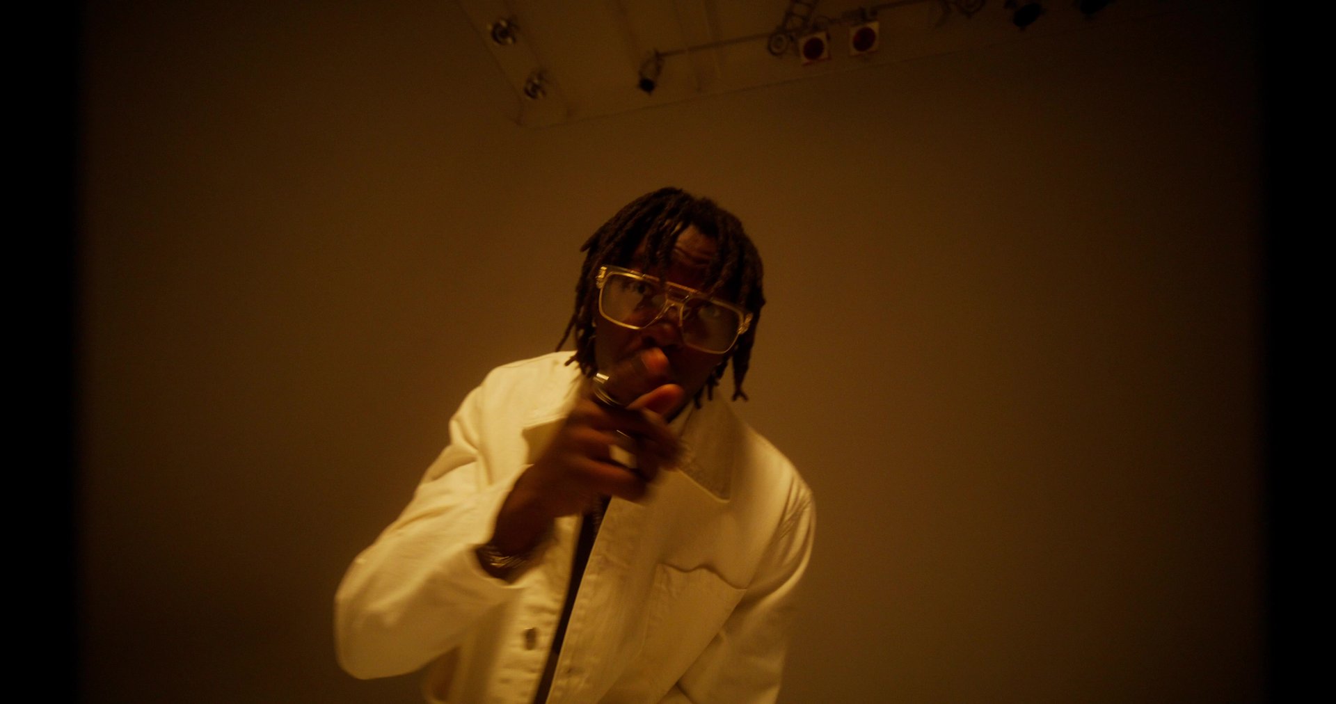 A stylish man raps while looking at the camera. Filming a music video in the studio