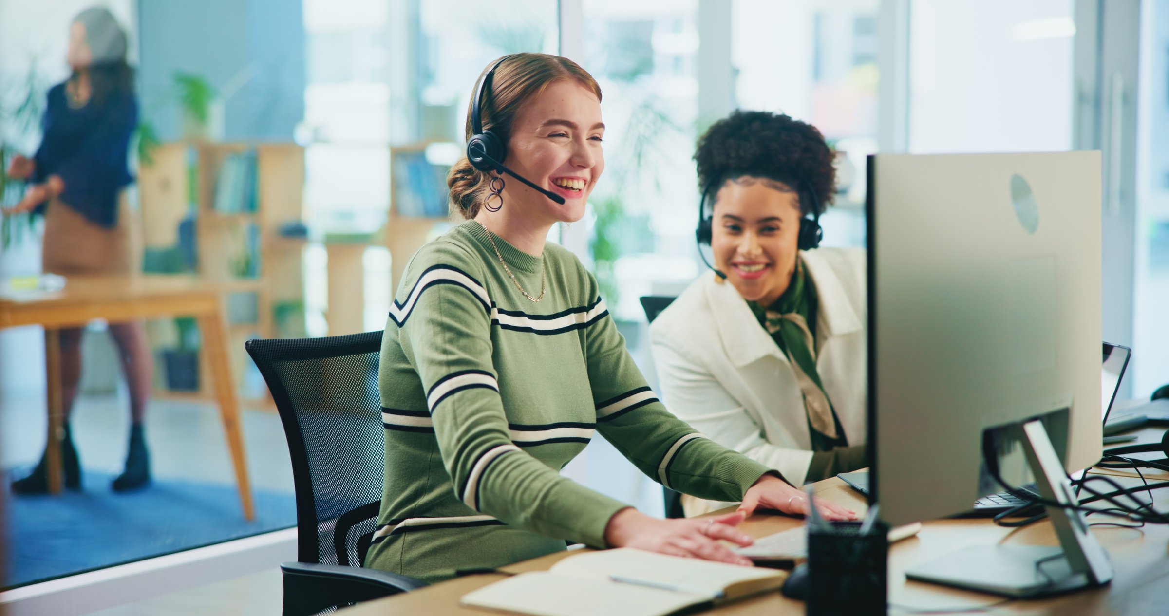 Happy customer service team with headsets working on computers