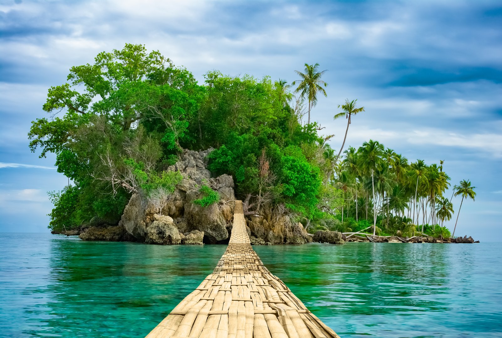 Bamboo pedestrian hanging bridge over sea to remote desert island. Beautiful tropical landscape. Travel lifestyle. Wild nature vacations. Adventure ecotourism concept. Way to Paradise. Exotic scenery
