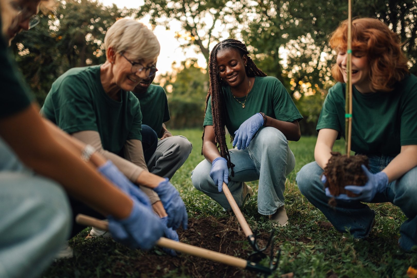 Diverse volunteers happily plant trees in park, promoting sustainability and eco friendly practices. Teamwork supports community and hope for greener future