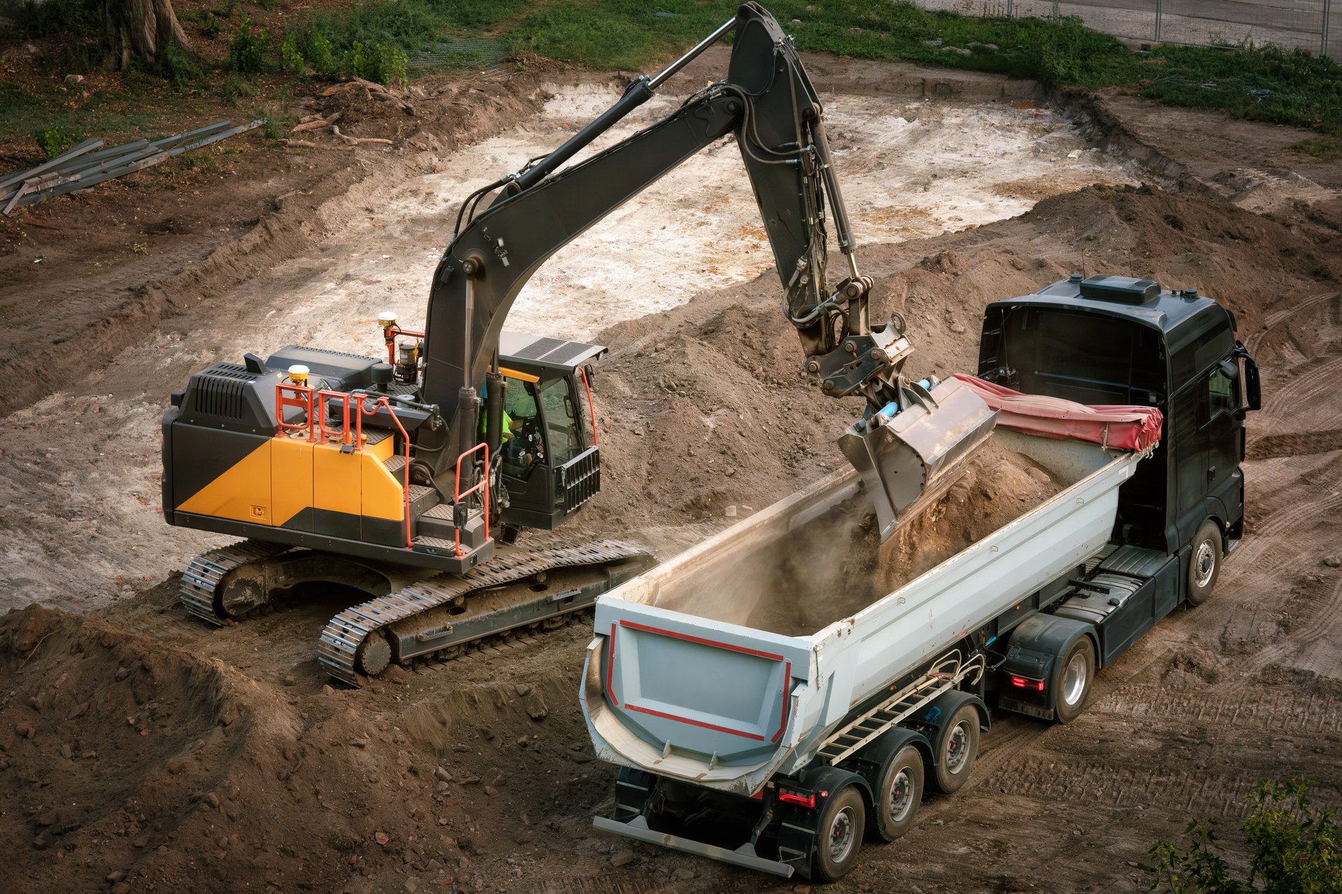 Excavator loading dirt into a dump truck on a construction site, nice view from above