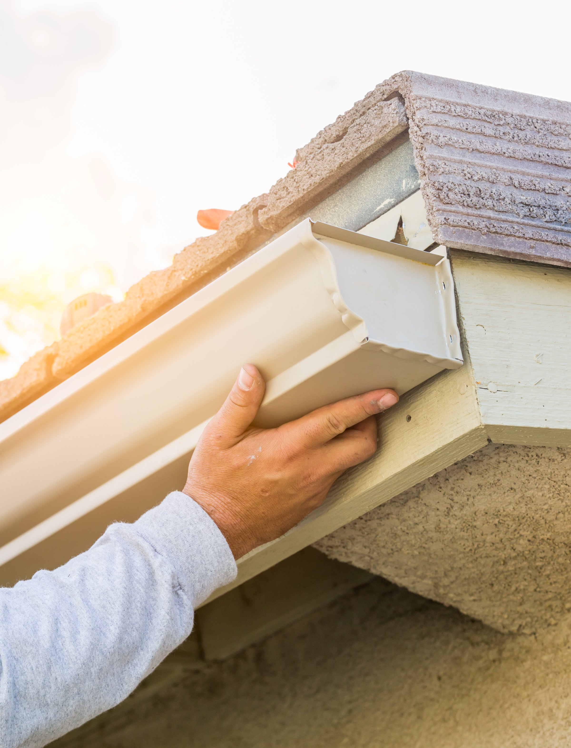 Worker Attaching Aluminum Rain Gutter to Fascia of House.Worker Attaching Aluminum Rain Gutter to Fascia of House.