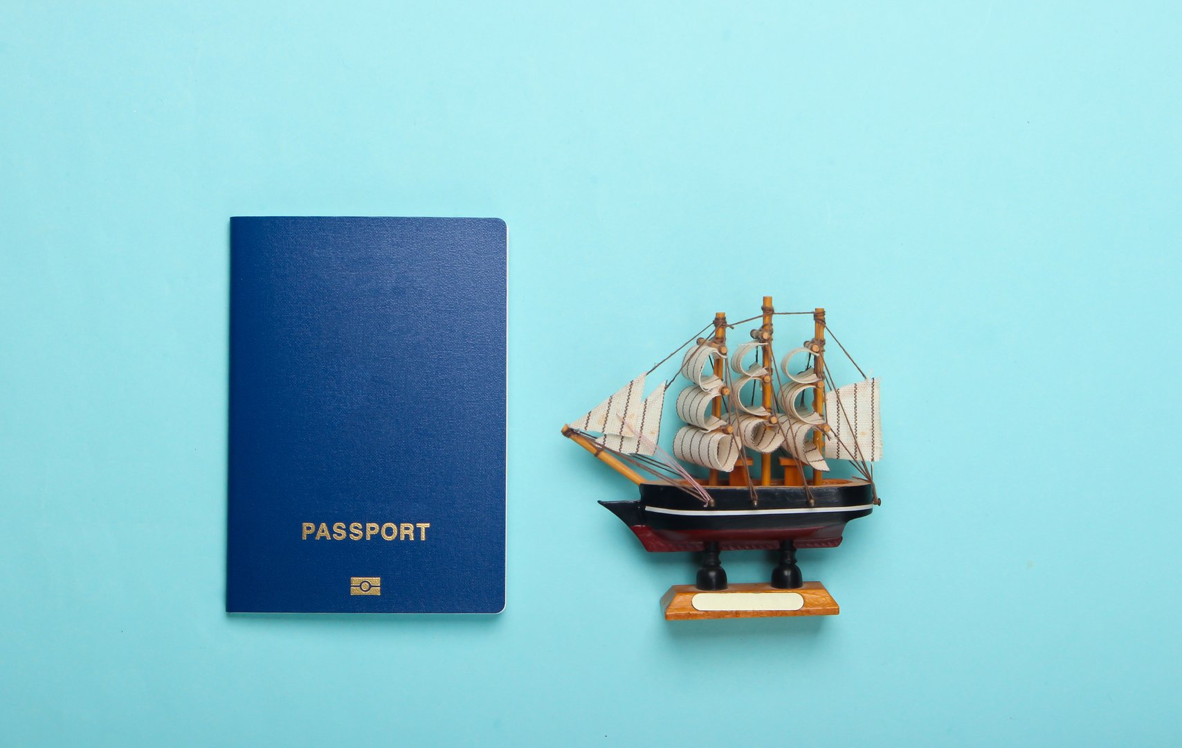Travel, cruise concept. Passport and ship figurine on a blue pastel background. Top view