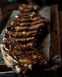 Grilled rib-eye steak sliced on a cutting board, showing char marks and juicy texture.