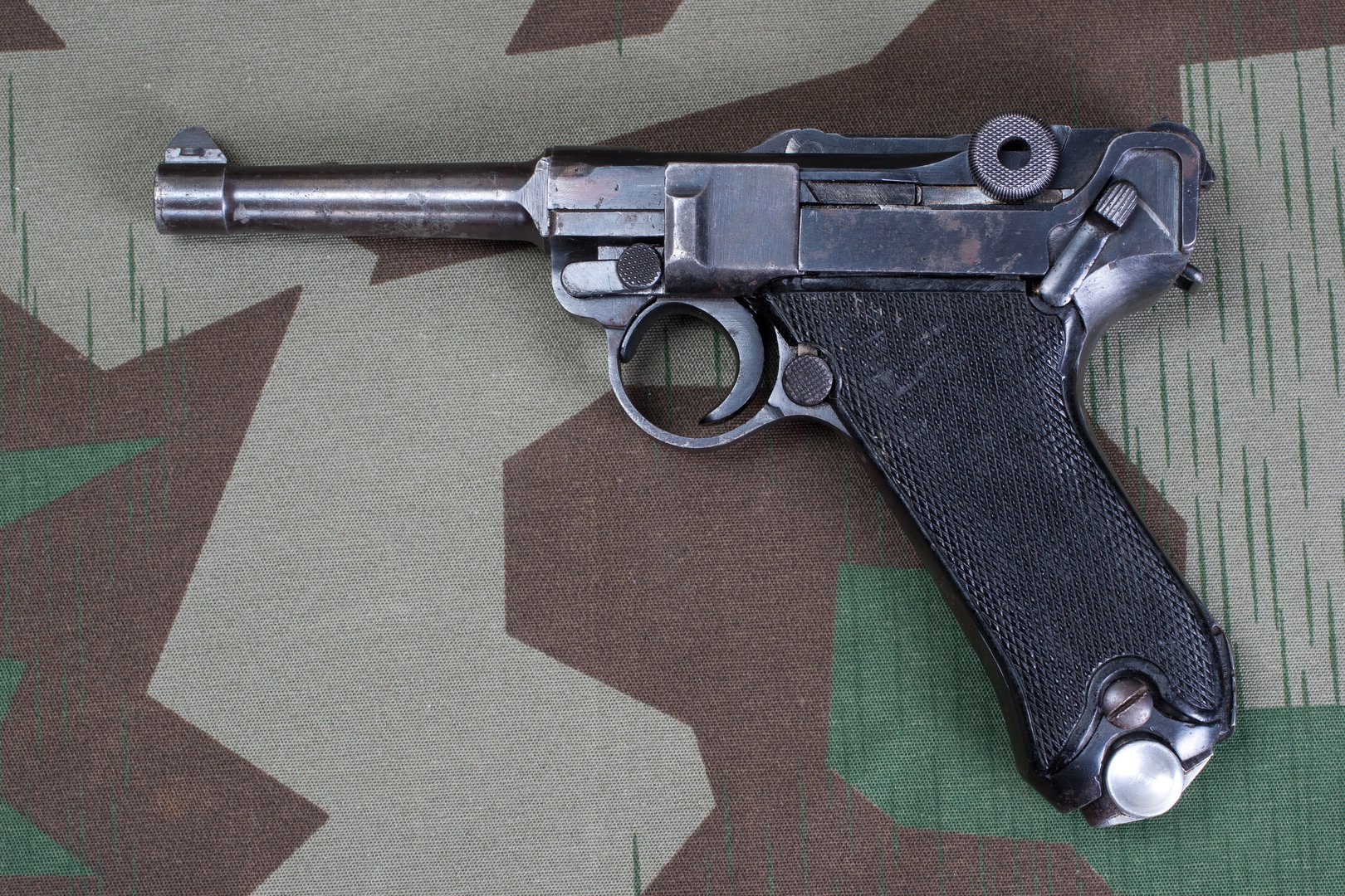 World War II period german army handgun with german award Iron Cross 1914 on camouflaged background