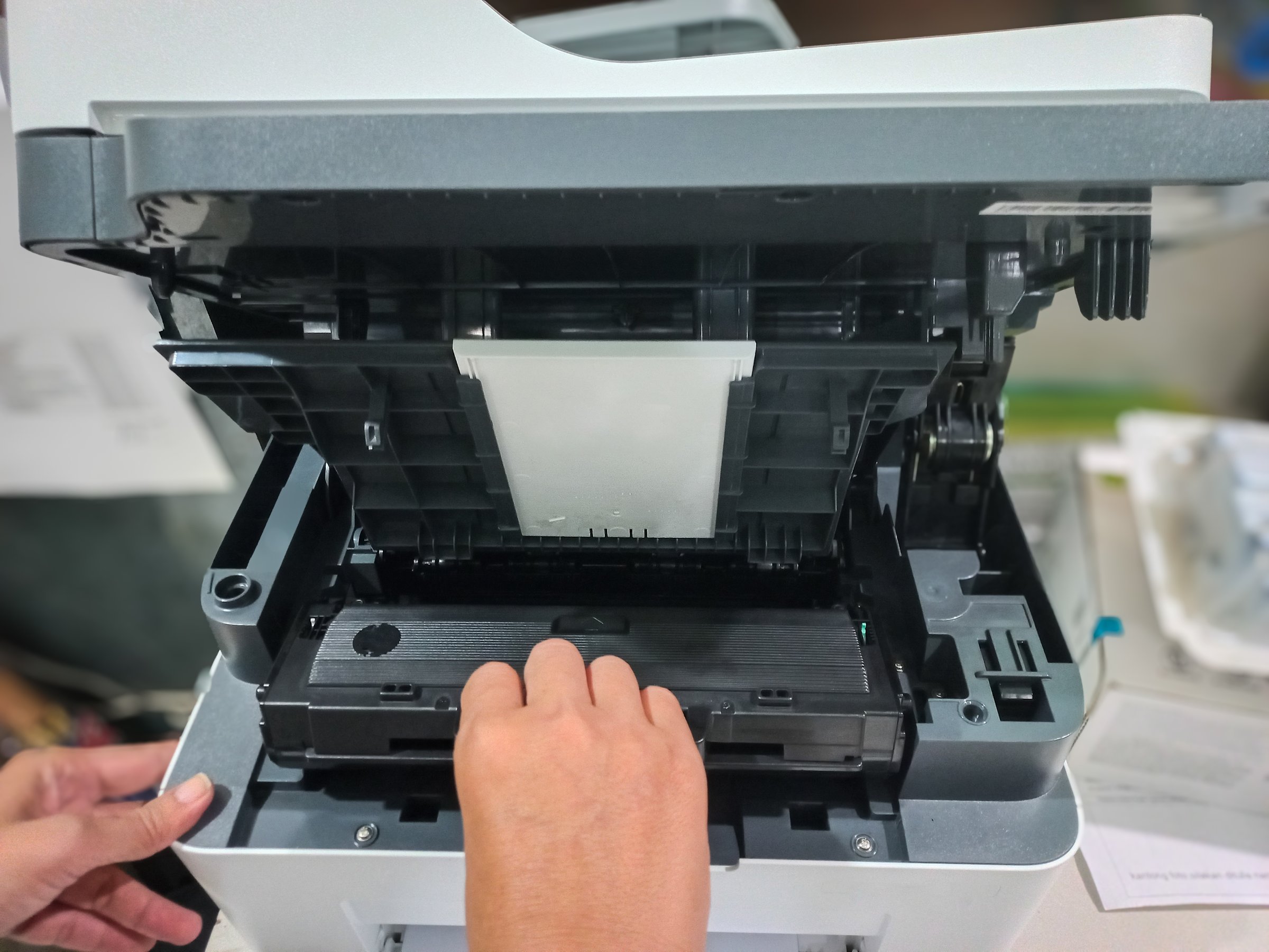 A man takes out a cartridge from a laser printer for maintenance and refilling toner. A man is reloading the printer cartridges of a laser jet printer.