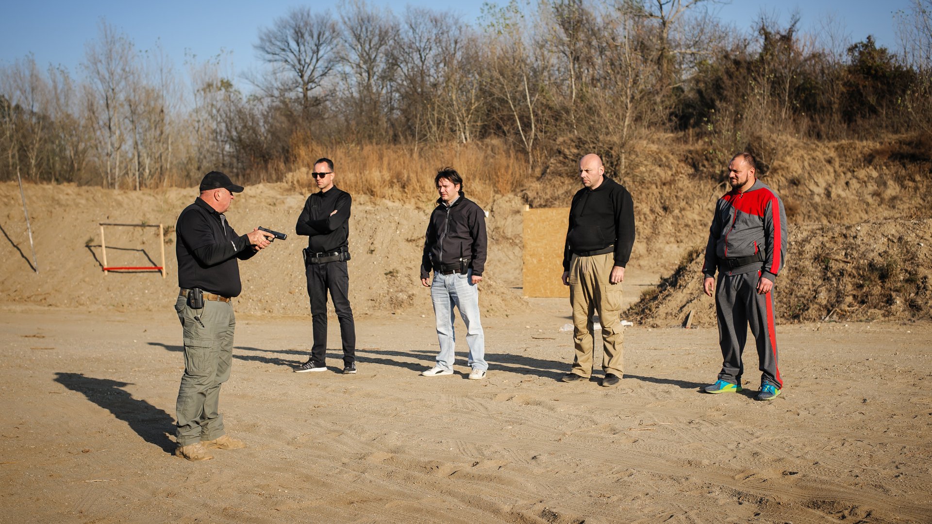 Shooting range instructor demonstrate gun shoot techniques to group of his students. Civilian team weapons training