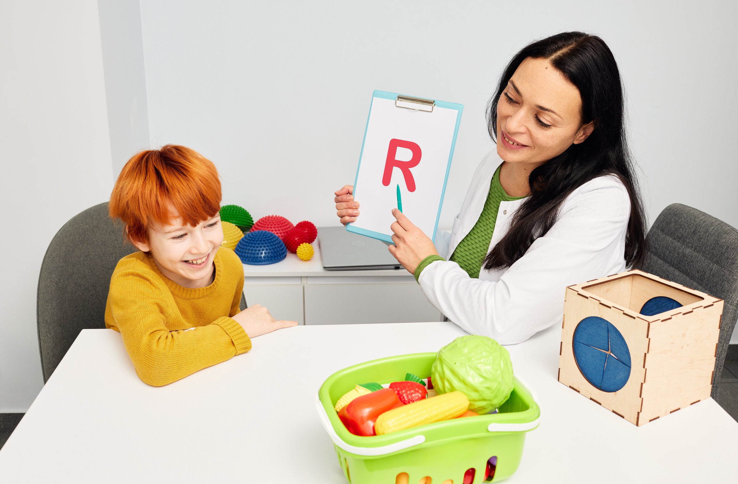 Professional speech and language therapist helping child patient with stuttering and difficulty in expressing language. Logopedic correction, pediatric speech and language therapy