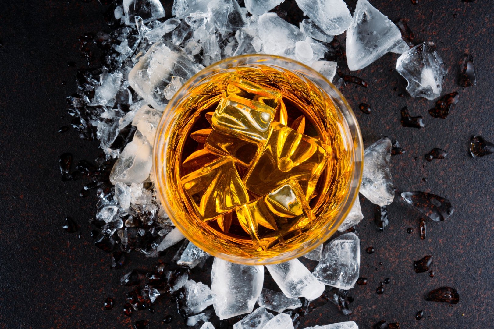 Glass of whiskey with ice cubes on black background