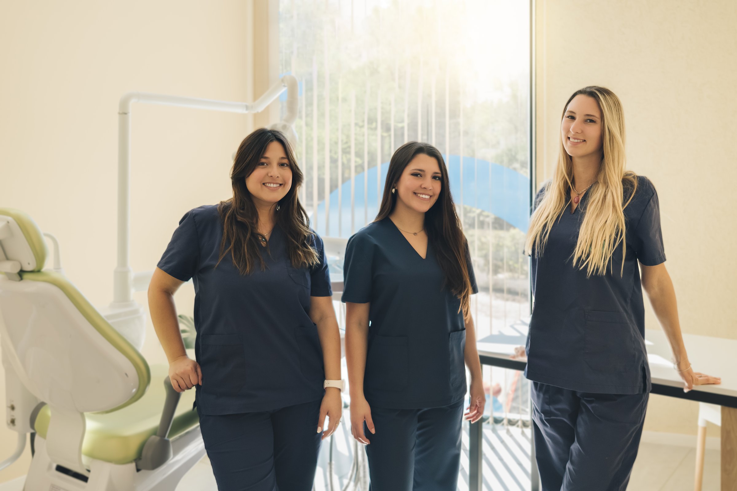 Concept of dentistry. Dental services. A team of professionals in a dental clinic. Three beautiful female dentists smile and look at camera in dental clinic.