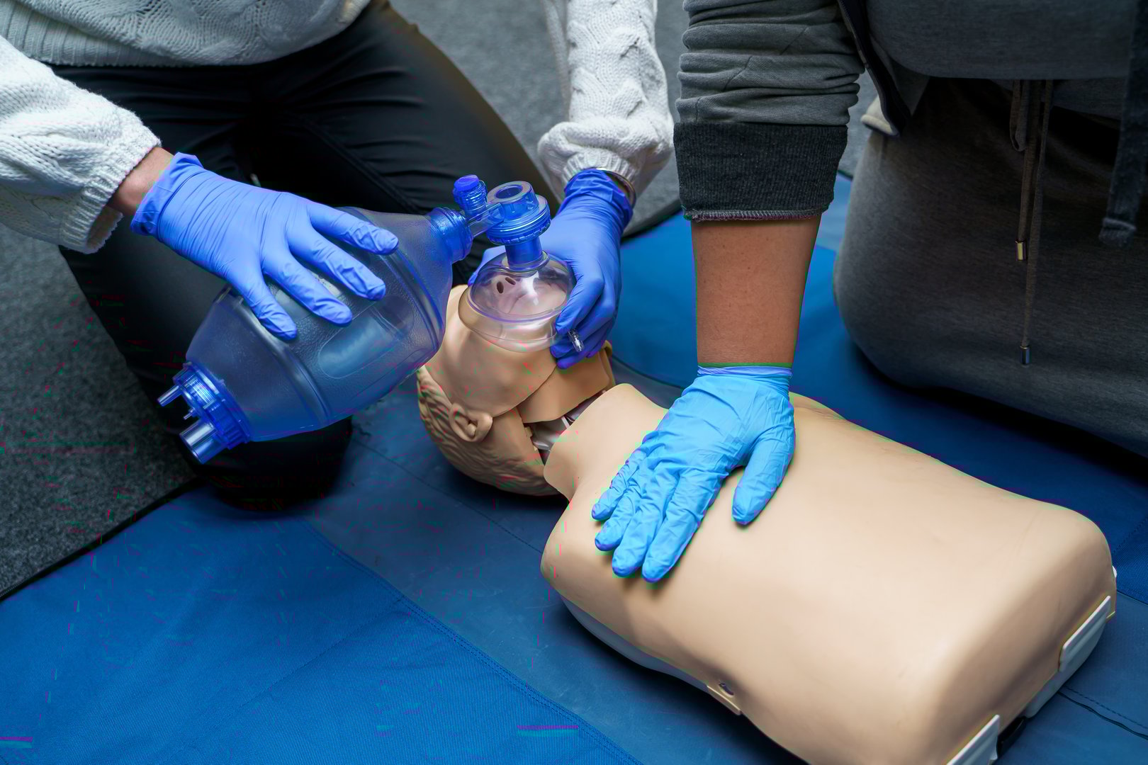 Man using CPR technique on dummy in first aid class. Oxigen mask on medical doll.