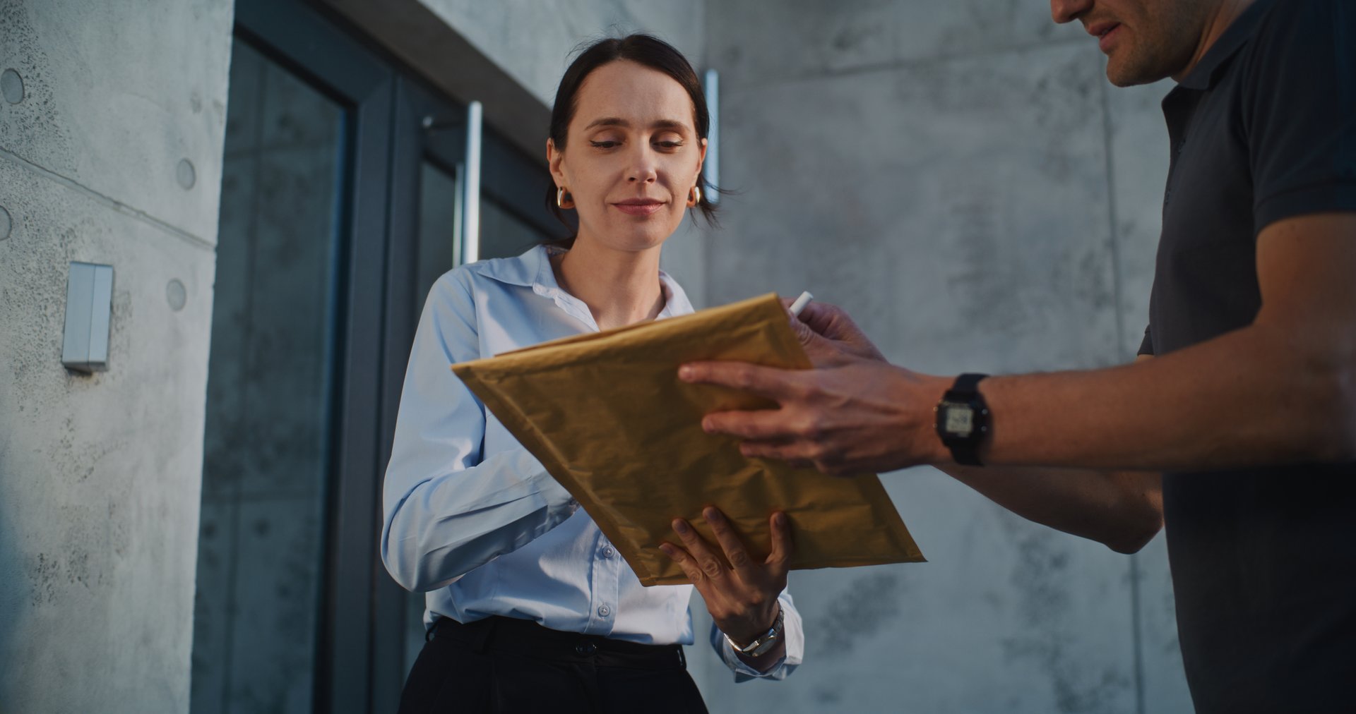 Postman Delivering Small Parcel for Recipient in Modern Office, Getting Client's Signature. Businesswoman Taking Padded Envelope with Online Shopping Order. Delivery or Postal Service. Slow Motion.