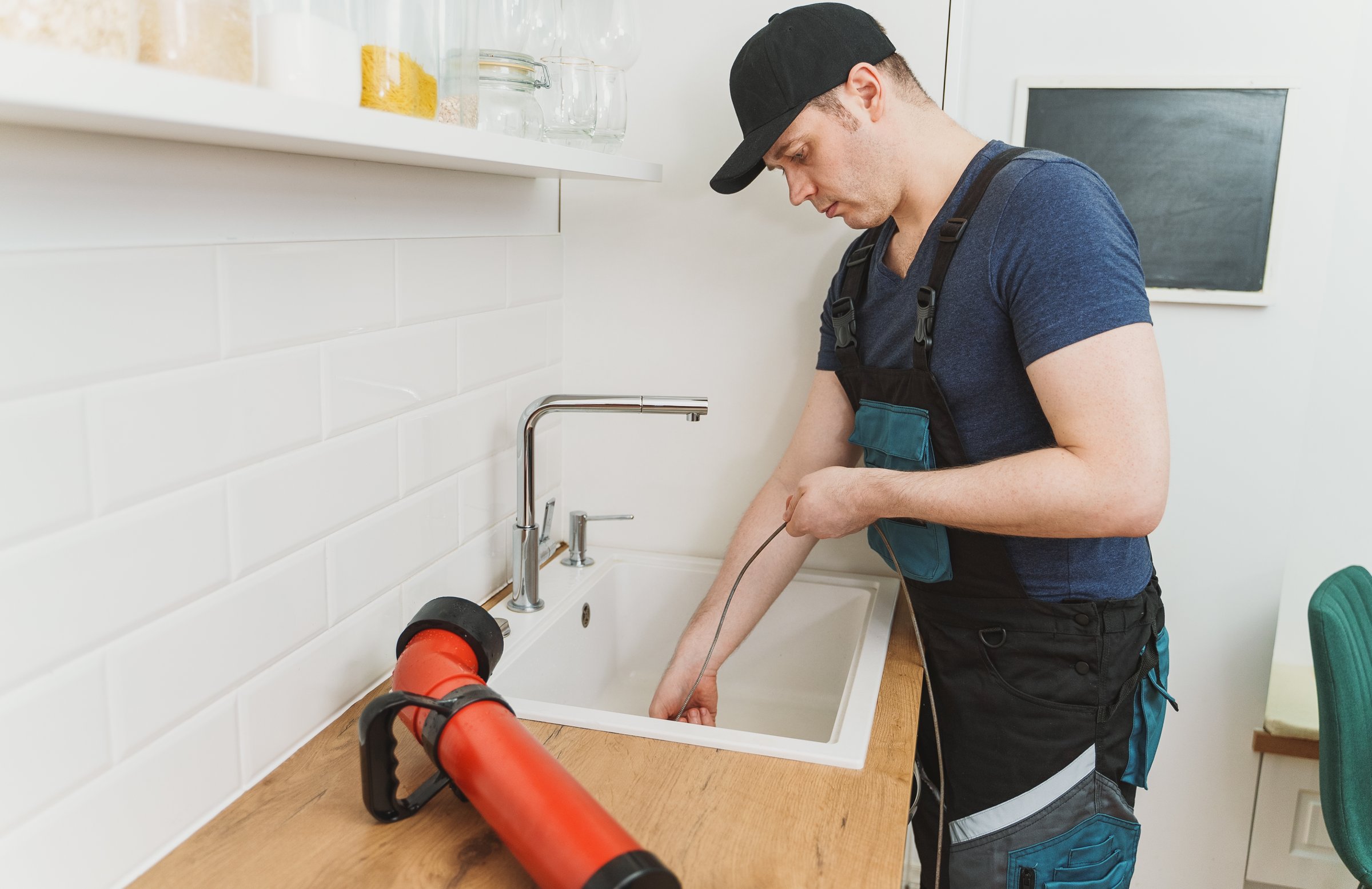 Plumber cleaning kitchen sink drain