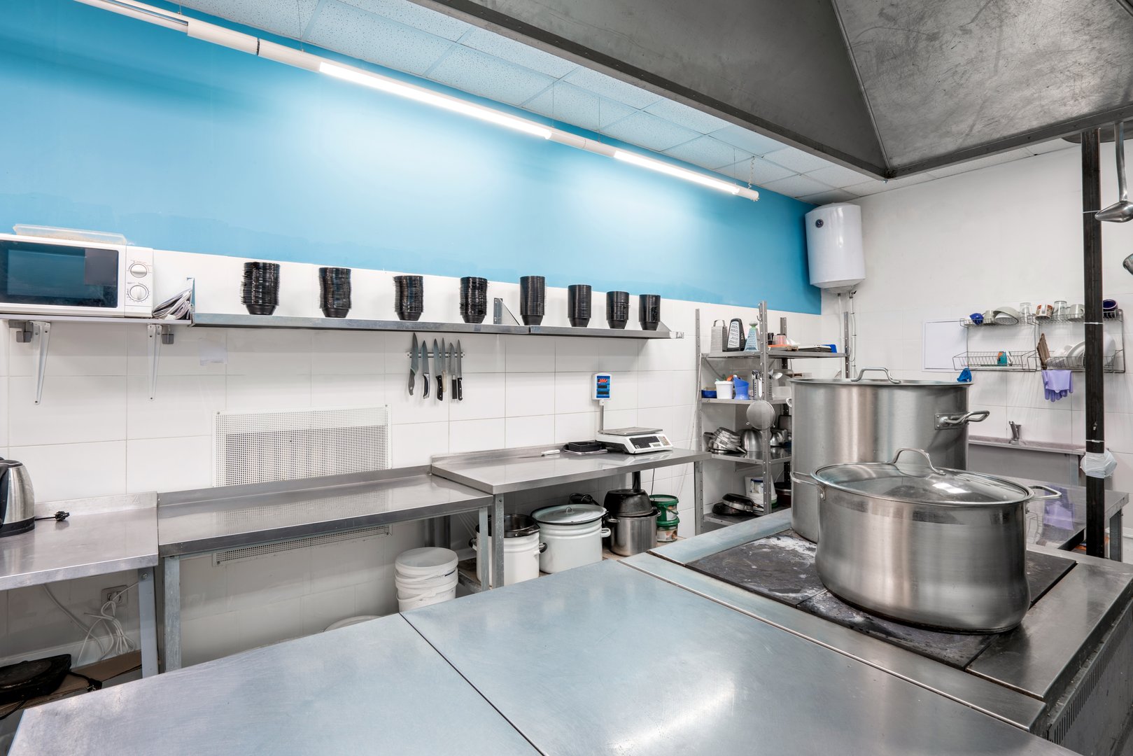 Modern restaurant kitchen with stainless steel kitchenware and equipment. Cooking with preparation tables, pans, pots, stoves