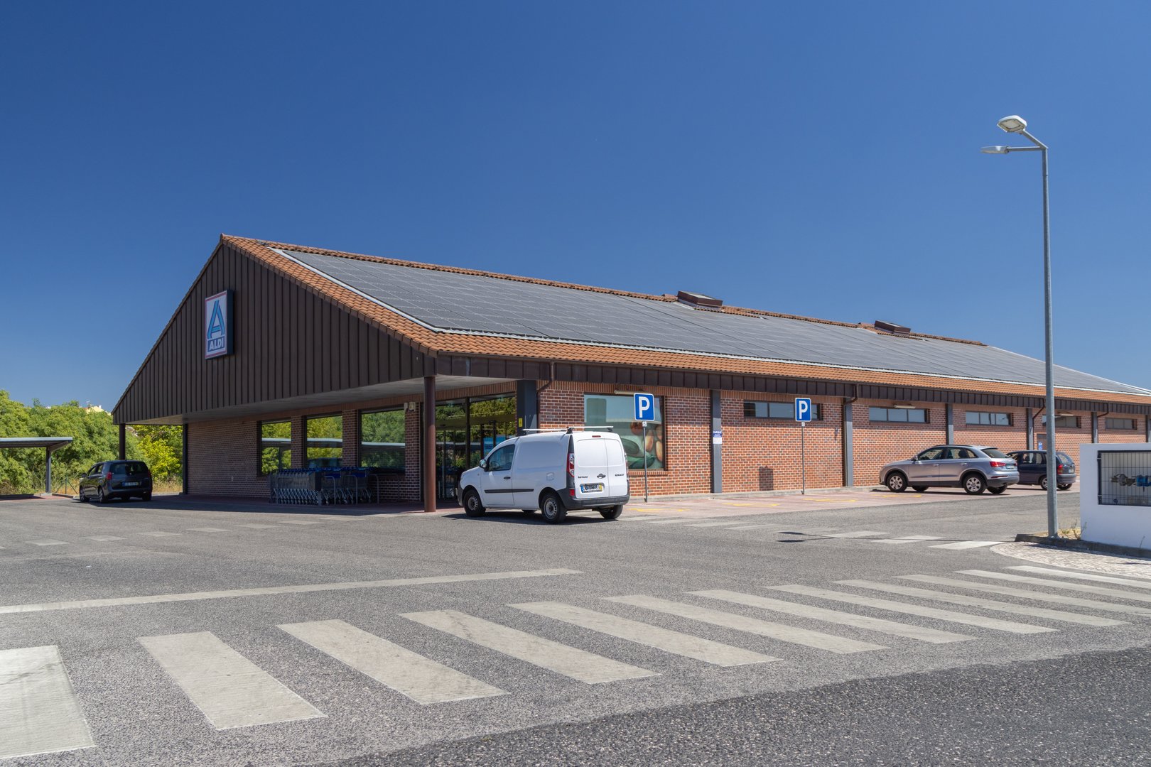 Lisbon, Portugal, August 20, 2025, Exterior view of an aldi supermarket building with solar panels installed on the roof, promoting sustainable energy practices