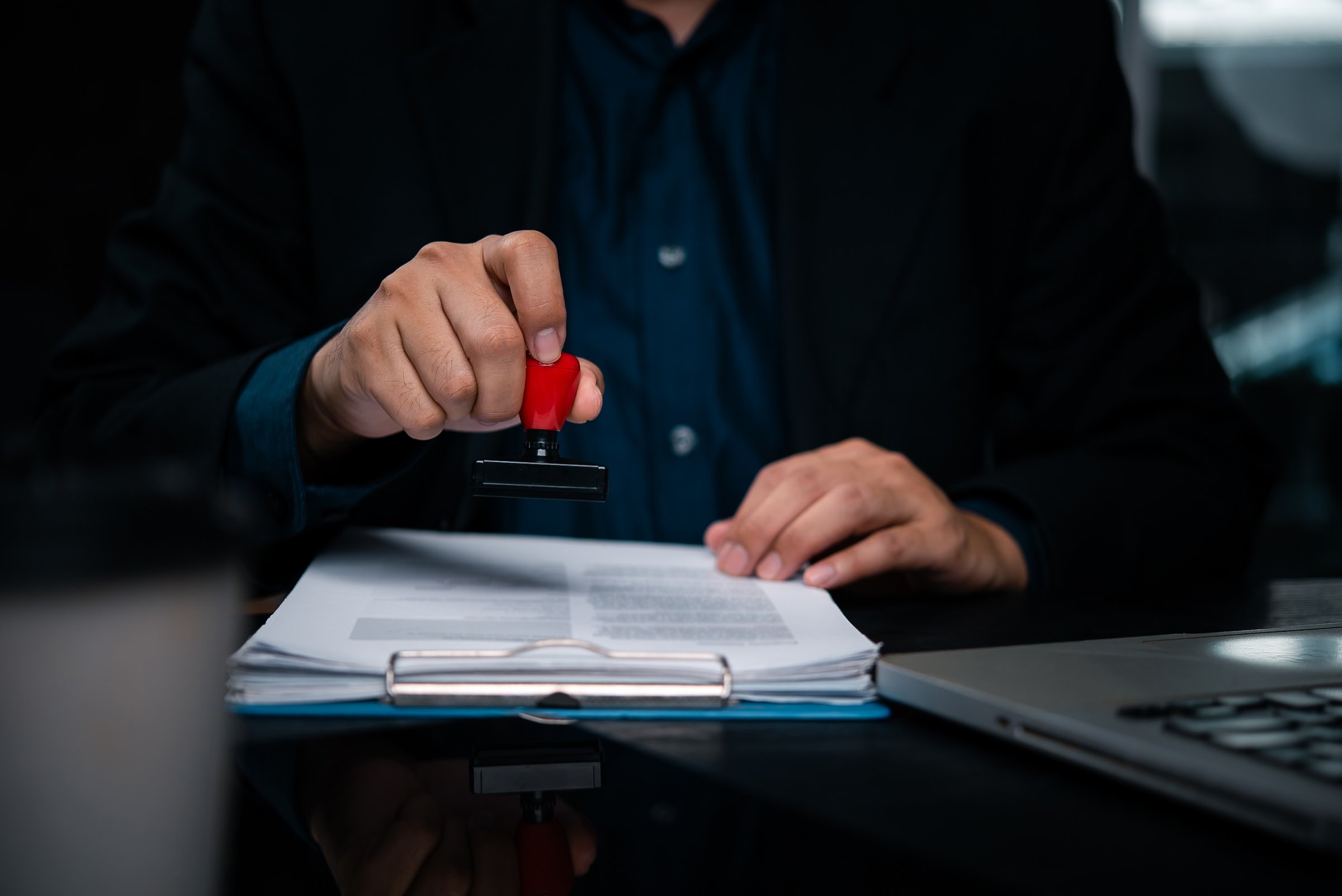 Business holding rubber stamp document approval verification. Corporate executive legal papers with official stamp document authentication. Notary service provider certify important business contract