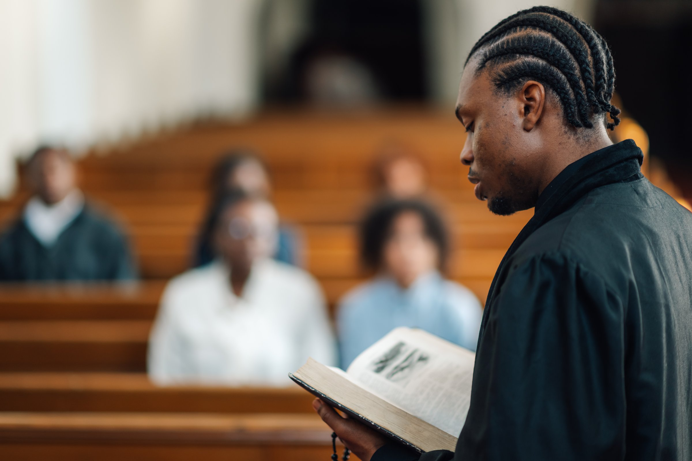 Young priest leads a congregation in prayer and reading from the holy book during a church service, creating a deeply spiritual atmosphere