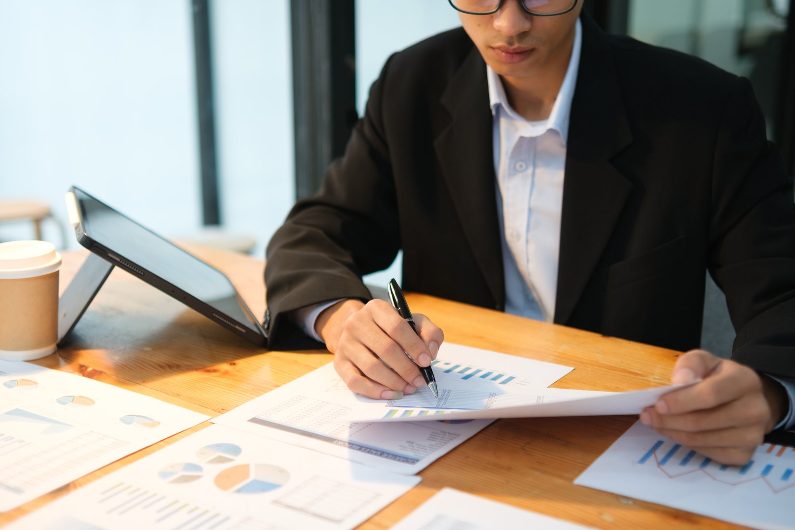 A business advisor focuses on reviewing financial charts and planning investment strategies in a modern office.