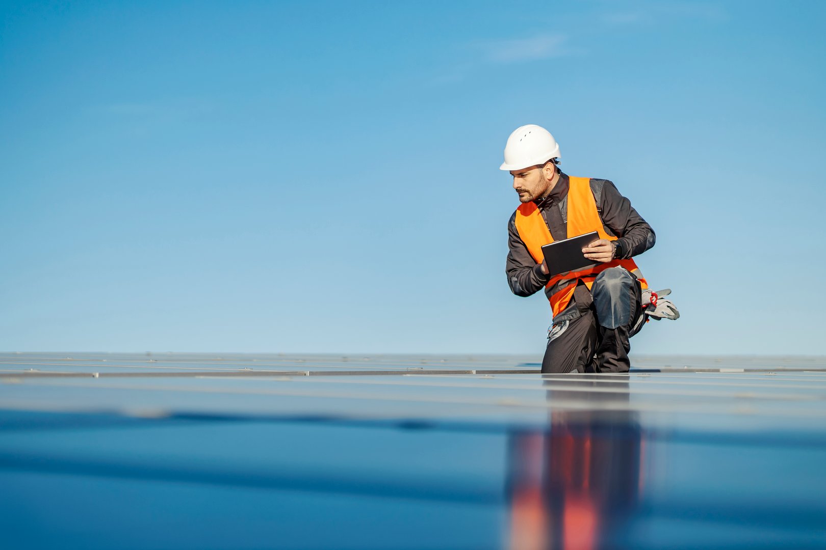 A handyman using tablet for solar panels testing on the roof.