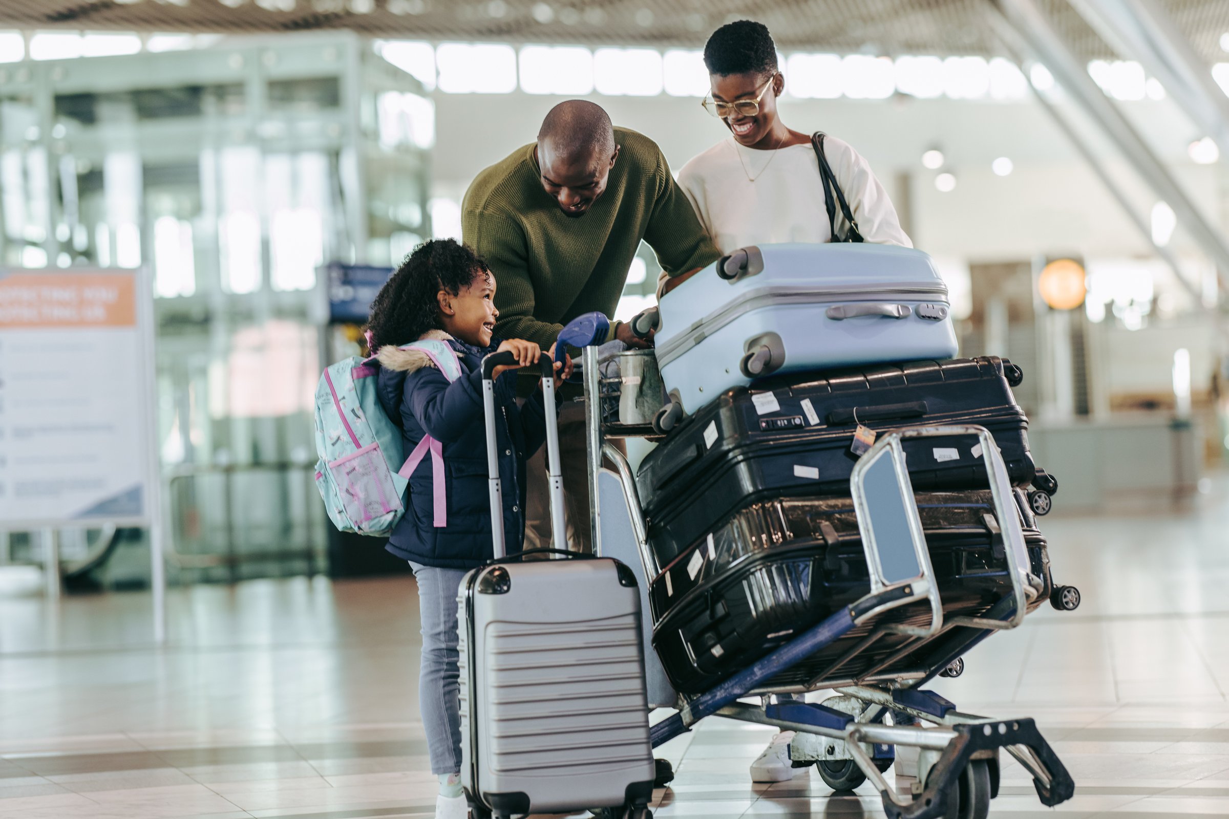African parents talking with their young daughter at airport while waiting for flight. Family of three at airport having fun while waiting at airport.