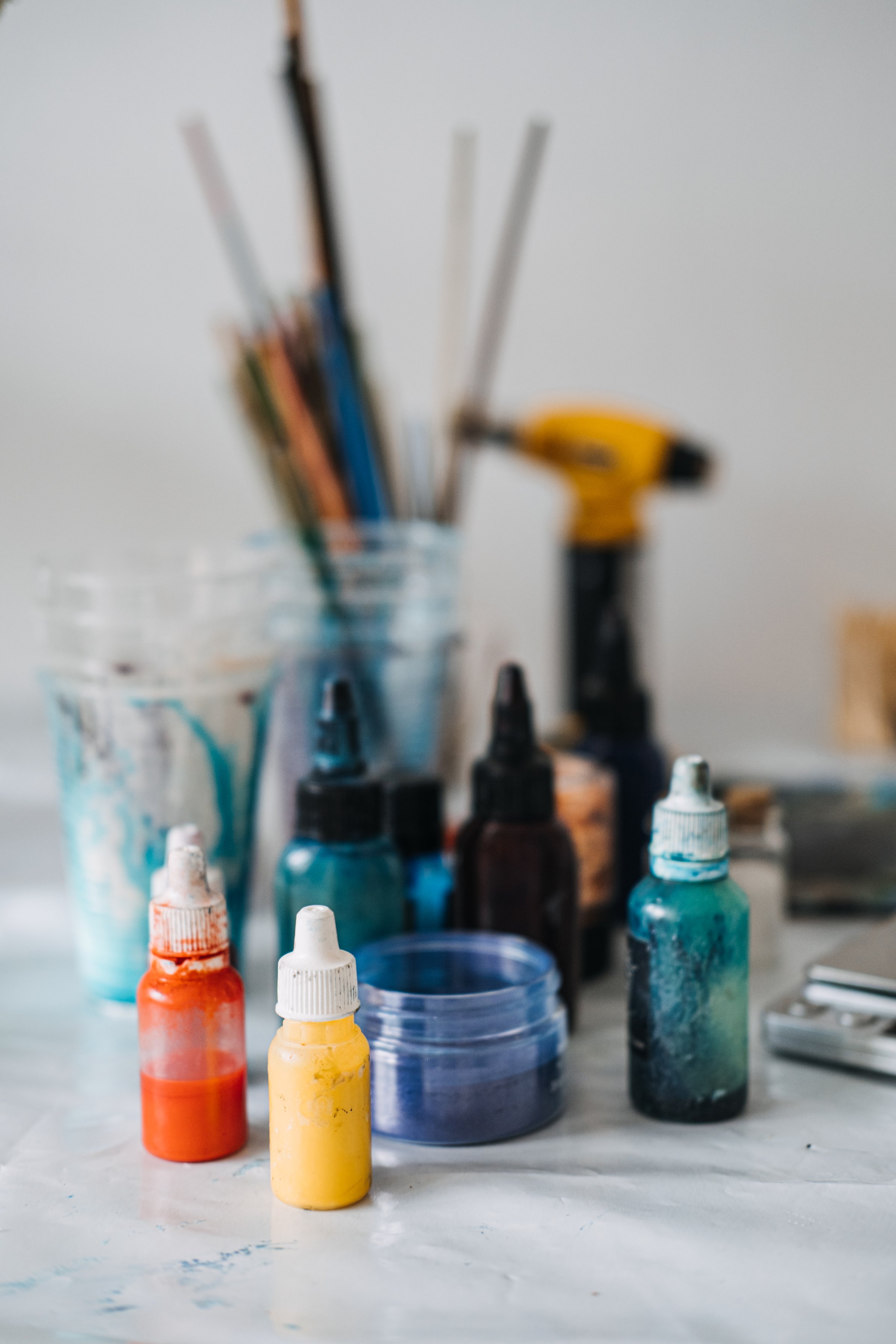 A colorful array of pigment bottles, mixing containers, and tools is displayed on a table in a DIY workspace. Artists prepare to create stunning epoxy resin art by selecting vibrant colors and mixing materials for their projects.