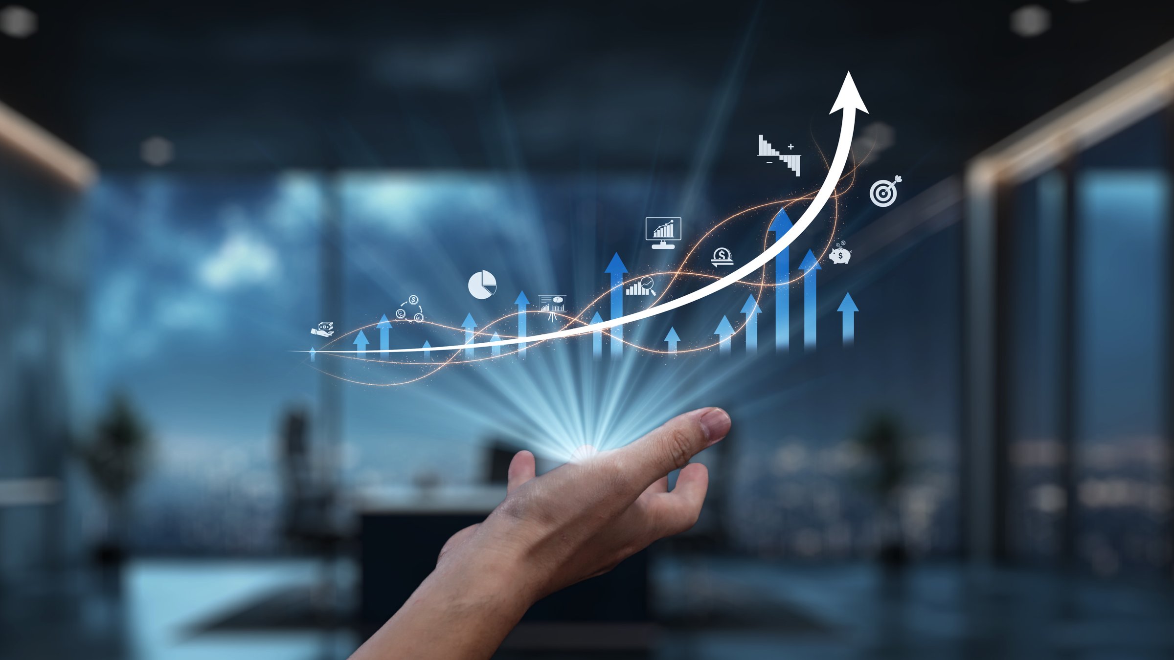A close-up of a hand reaching out towards a digital growth graph featuring various charts and arrows in a sleek office setting, symbolizing potential and success. Auvana